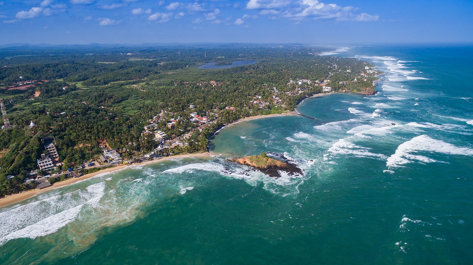 Aerial view of Mirissa's curved beach, palm trees and turquoise sea